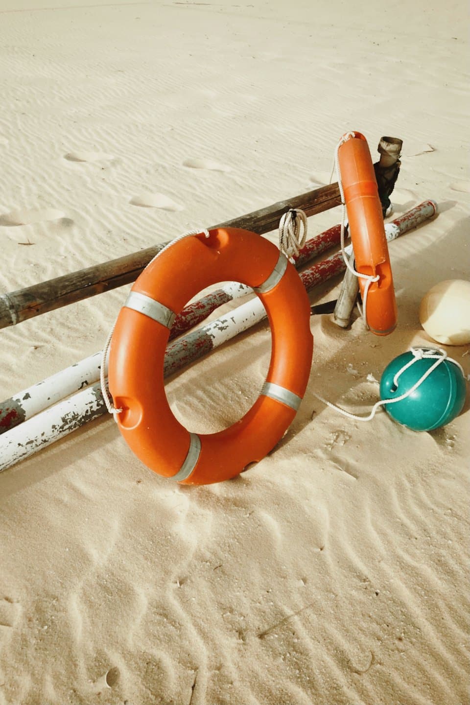 Safety buoys and poles rest on the sandy beach.