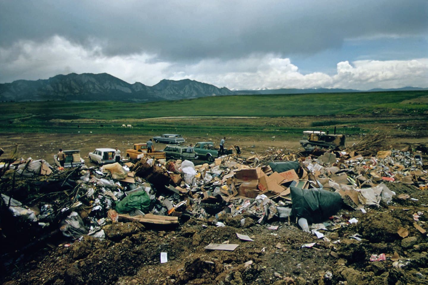 People working at a landfill with piles of waste and machinery.